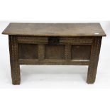 A 17TH CENTURY OAK COFFER with plank top, panelled front, chip carved decoration and standing on