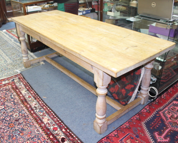 A RECTANGULAR TOPPED PINE REFECTORY TABLE with turned supports united by a stretcher, the top 81cm x