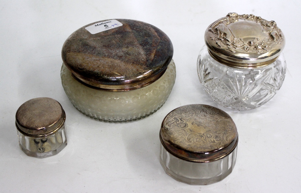 A GROUP OF FOUR CUT GLASS JARS with white metal lids, each marked sterling, the largest 12cm