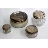 A GROUP OF FOUR CUT GLASS JARS with white metal lids, each marked sterling, the largest 12cm