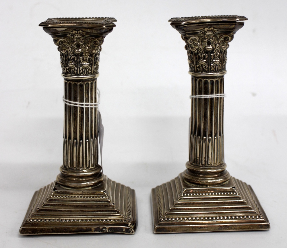 A PAIR OF BIRMINGHAM SILVER CORINTHIAN COLUMN CANDLESTICKS on spreading square base 16cm high (2)