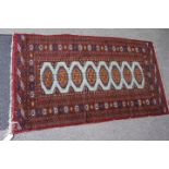 AN OLD MIDDLE EASTERN RED GROUND RUG with geometric decoration, 93cm x 162cm and a further red