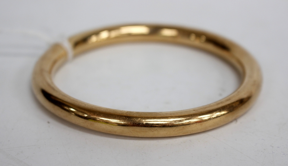 A YELLOW METAL BANGLE marked with 15ct and with inscription to the inside 8cm across