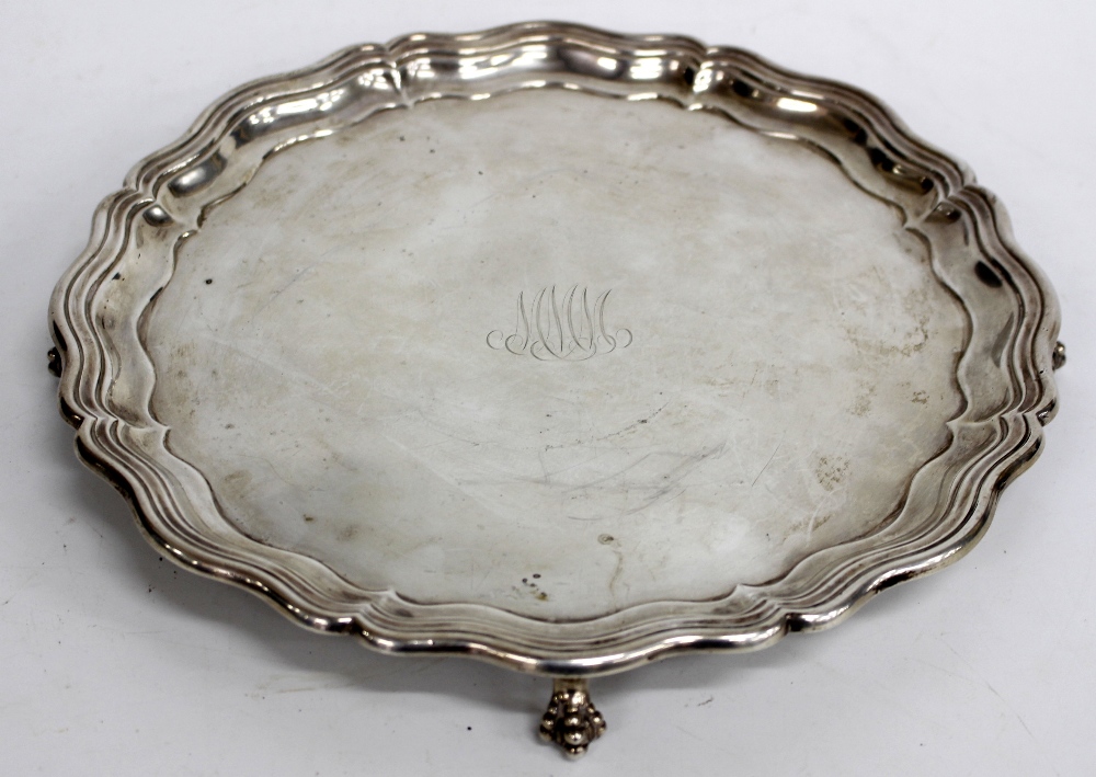 A SHEFFIELD SILVER SERPENTINE EDGE SALVER standing on ball and claw feet, engraved with initial '