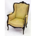 A FRENCH MAHOGANY CARVED WING ARMCHAIR with gold and brocade upholstery, 103cm high