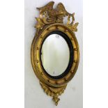 A 19TH CENTURY GILT CONVEX WALL MIRROR with eagle cresting to the top, 83cm