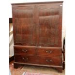 A GEORGIAN MAHOGANY LINEN PRESS with twin panelled doors above two short and one long drawer, raised