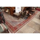 A 20TH CENTURY MIDDLE EASTERN GEOMETRIC PATTERN RUG on a red ground, decorated with flowers and vine