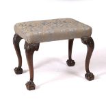 A GEORGIAN STYLE MAHOGANY STOOL with overstuffed upholstered seat and with acanthus leaf carved