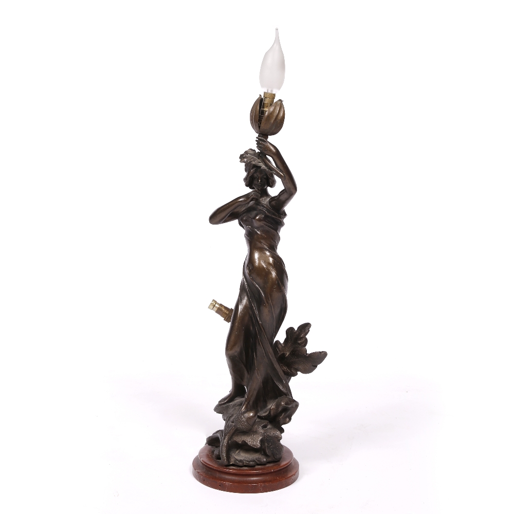 A SPELTER TABLE LAMP in the form of young woman holding a branch aloft, mounted on a turned marble