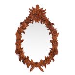 A VICTORIAN BLACK FOREST TYPE CARVED PINE OVAL WALL MIRROR with flowering laurel branch
