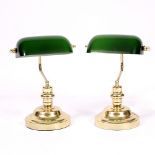 A PAIR OF BRASS DESK LAMPS with green glass shades and circular bases, each approximately 37cm high