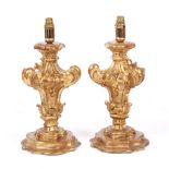 A PAIR OF GILT CARVED WOOD TABLE LAMPS of scrolling form on shaped bases, each 43cm high