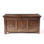 A 17TH CENTURY OAK COFFER with chip carved triple panel front and standing on stile feet, 119cm wide