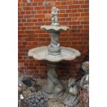 A LARGE COMPOSITE STONE TWO TIER GARDEN FOUNTAIN of classical dolphin form, mounted with a cherub,