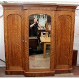 A VICTORIAN BREAKFRONT TRIPLE WARDROBE with a central mirrored door and panel doors to either