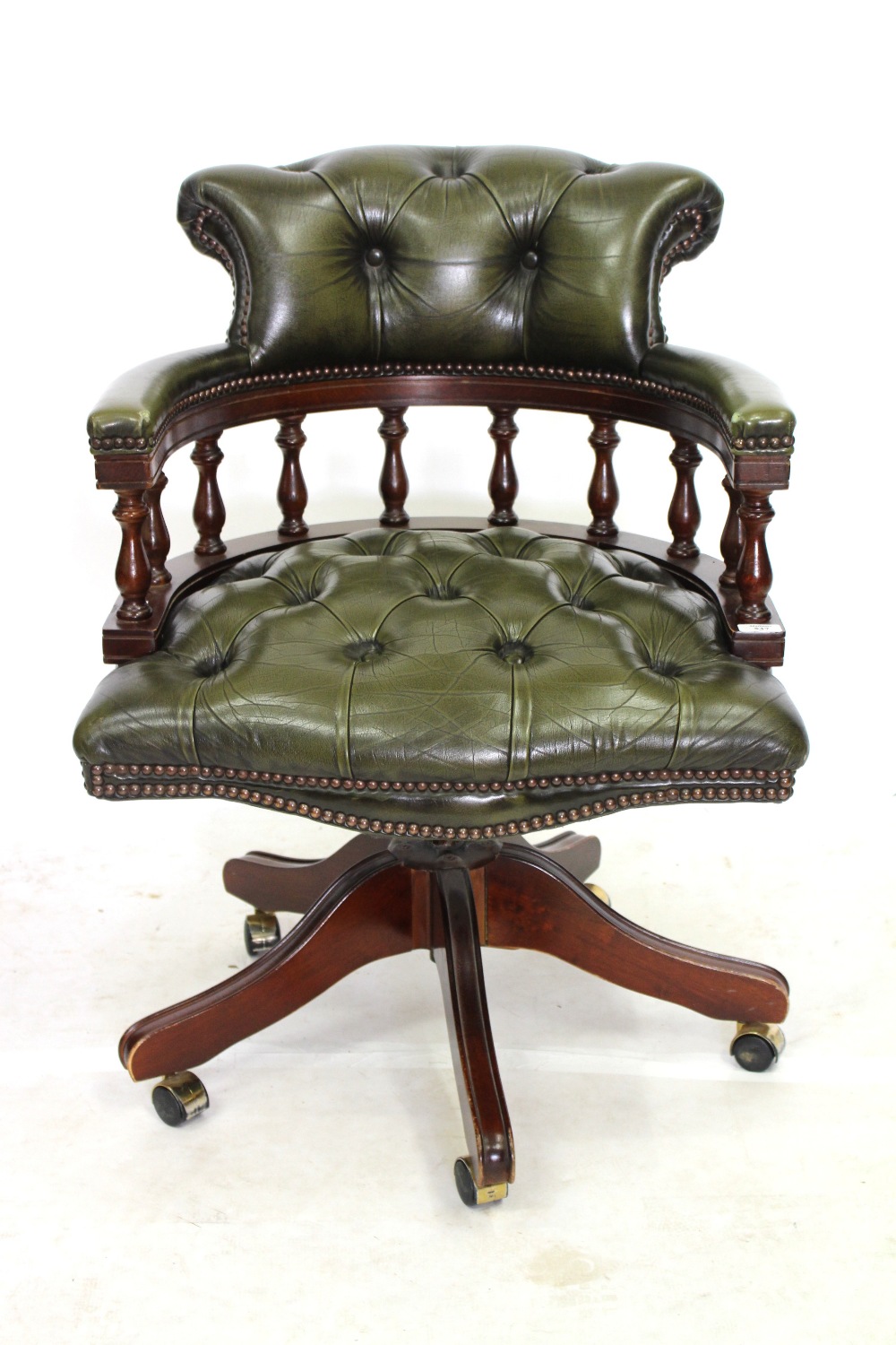 A GREEN LEATHER BUTTON UPHOLSTERED SWIVELLING DESK CHAIR with turned supports
