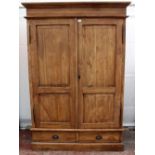 A DOUBLE TEAK WARDROBE with fielded panelled doors above two fitted frieze drawers, standing on a