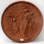 A CIRCULAR TERRACOTTA WALL PLAQUE decorated with a classical female figure playing pipes, the