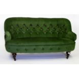 A VICTORIAN GREEN VELOUR BUTTON UPHOLSTERED TWO SEATER SETTEE on turned ring legs terminating in