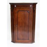 A GEORGE III OAK CORNER CABINET with canted corners, a shaped cornice and fielded panel door, 127.