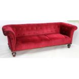 A 19TH CENTURY RED VELVET UPHOLSTERED CHESTERFIELD SOFA standing on carved feet, 218cm wide