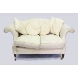 A TWO SEATER UPHOLSTERED SETTEE with scrolling arms and turned legs, terminating in brass casters,