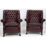A PAIR OF OXBLOOD COLOURED LEATHER BUTTON UPHOLSTERED ARMCHAIRS standing on claw and ball feet, 98cm