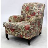 AN OLD DEEP ARMCHAIR with floral upholstery, fitted cushions, square tapering legs and brass