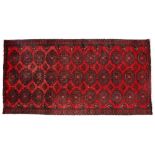 A BELOUCH RED GROUND RUG with hexagonal medallion repeating pattern and banded border 227cm x 110cm