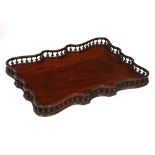 A GEORGE III MAHOGANY GALLERIED TRAY of serpentine rectangular outline with turned balusters to