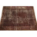 AN ANTIQUE PERSIAN RED GROUND SMALL CARPET with a banded border and all over geometric decoration,