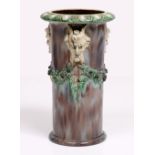 A VICTORIAN MAJOLICA POTTERY VASE of cylindrical form with satire head mounts and wreath decoration,