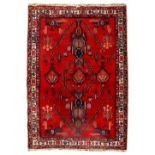 AN EASTERN CAUCASIAN STYLE RED GROUND RUG with all over polychrome geometric design, within a triple