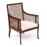 A GEORGE III MAHOGANY BERGERE LIBRARY ARMCHAIR with turned tapering legs terminating in later