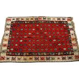 A KELIM with red central ground and a cream ground border with polychrome decoration 202cm x 305cm