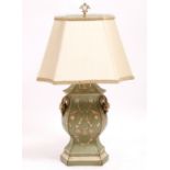 A GREEN AND CREAM PAINTED TABLE LAMP with foliate scroll decoration and with pomegranate handles,
