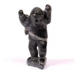 AN INUIT SOAPSTONE CARVED SCULPTURE depicting a huntsman, bearing his catch on his back, signed