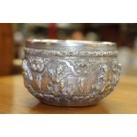 AN ANTIQUE BURMESE WHITE METAL BOWL chased and engraved with various figures masks and foliate bands