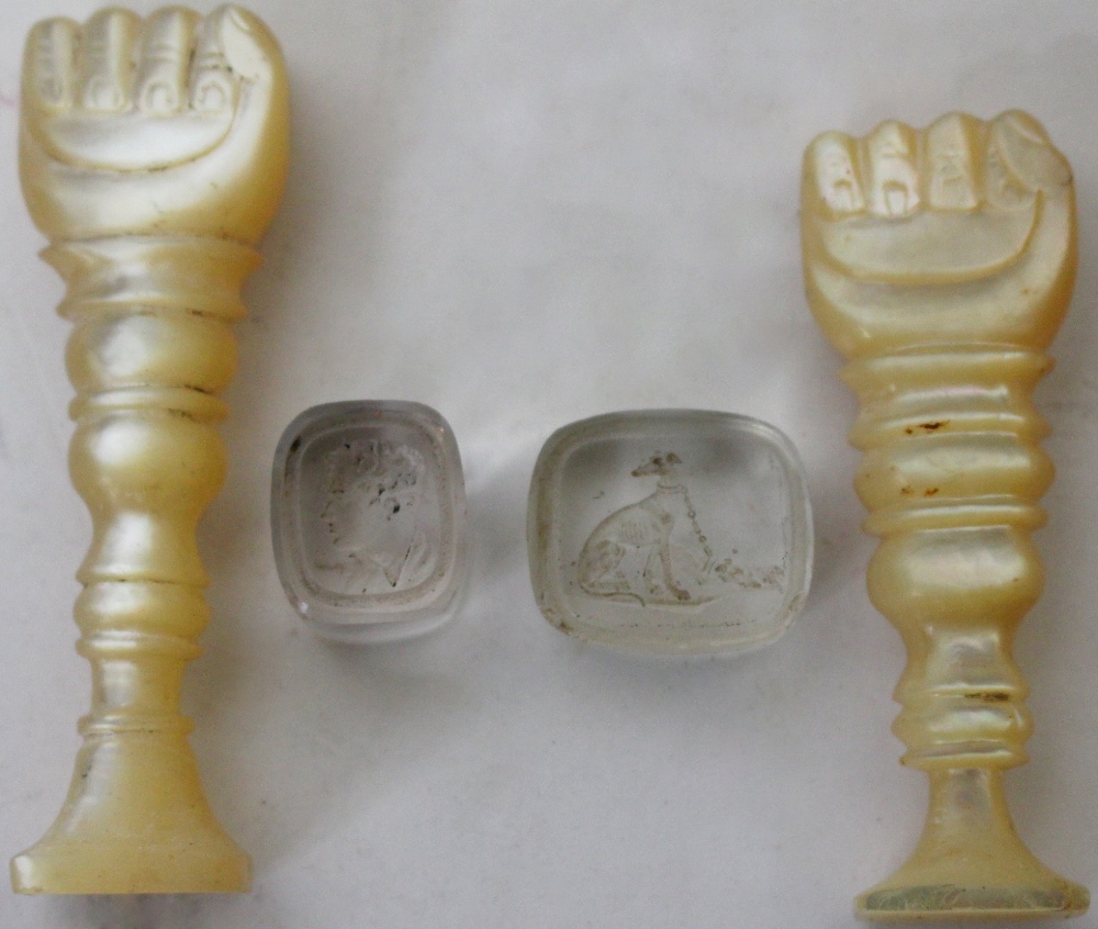 TWO VICTORIAN CARVED MOTHER OF PEARL SEALS in the form of fists together with two red crystal seal