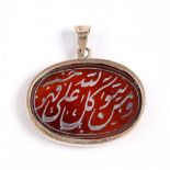 An Islamic oval pendant 19th Century engraved to one side with Nastaliq script in gold metal