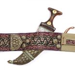 A Qajar Jambiya dagger in gold metal inlaid scabbard with embroidered belt having Damascene type