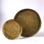 Two brass Ottoman petal-edged trays each embossed with scripture and foliate patterns, 46cm and 31cm