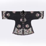 A Chinese black silk ladies jacket circa 1900-1920 with embroidered flower roundels, bird and wave
