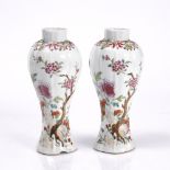 A pair of Chinese famille rose slender vases 18th Century each with rock work and prunus, 22cm high