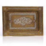 An Islamic brass tray with silver metal inlay and central calligraphy panel, 27cm x 19.5cm