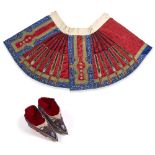 A Chinese red silk skirt 19th Century together with embroidered shoes, the skirt having blue bands