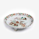 A Chinese famille verte scalloped dish 18th/19th Century raised on three porcelain supports with