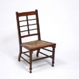 Manner of Liberty & Co. Nursing chair, circa 1890 with drop in rush seat and turned supports 69cm