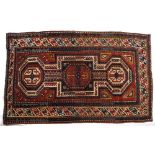 A Kazak keyhole rug of red ground with geometric medallions, 174cm x 102cm